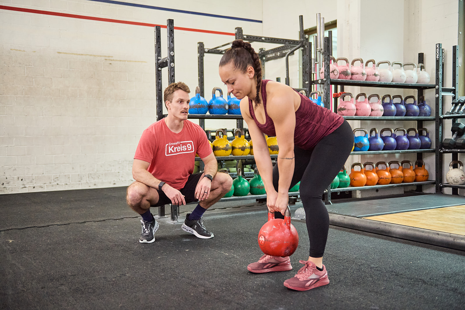 a lady lifting a kettlebell with a personal trainer